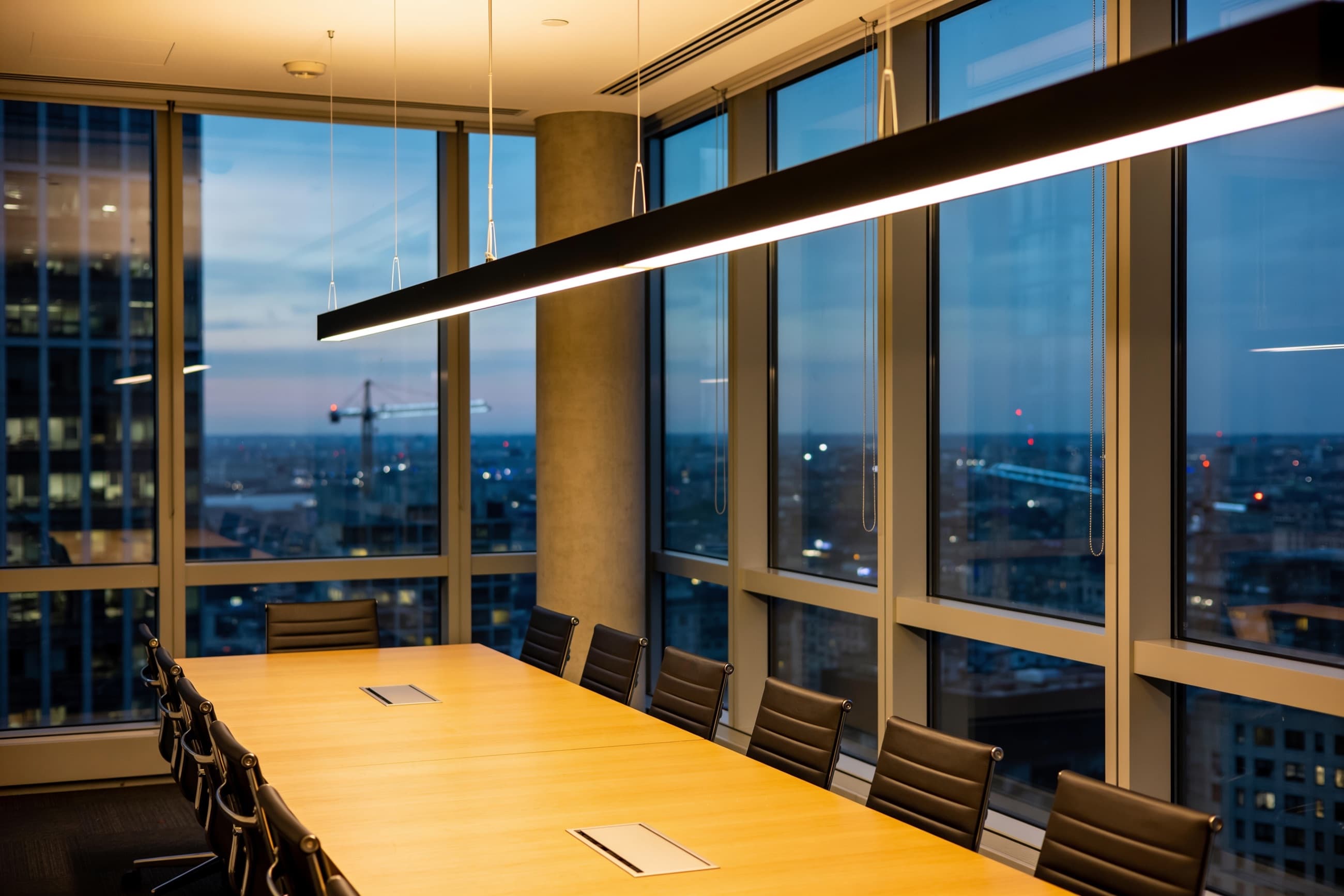 An empty boardroom overlooking the city at dusk.
