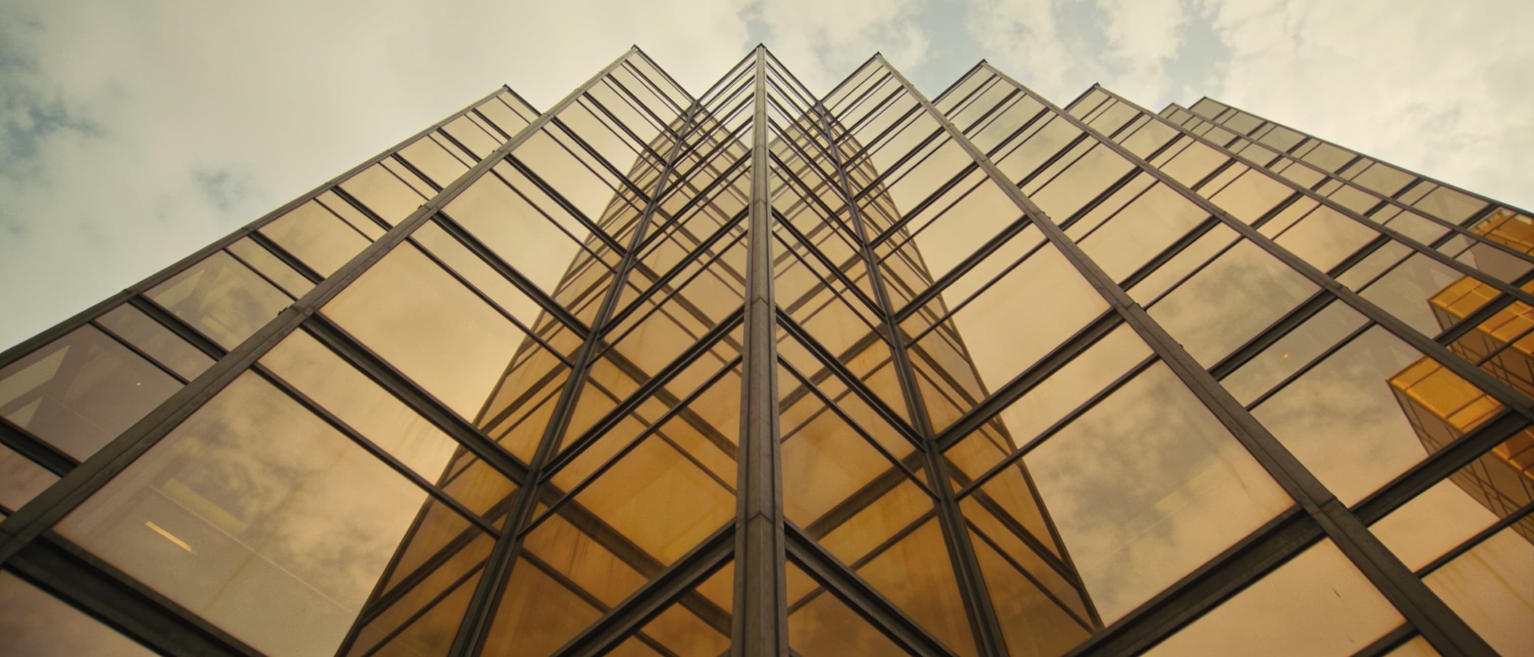 Golden glass office tower facade seen from below.